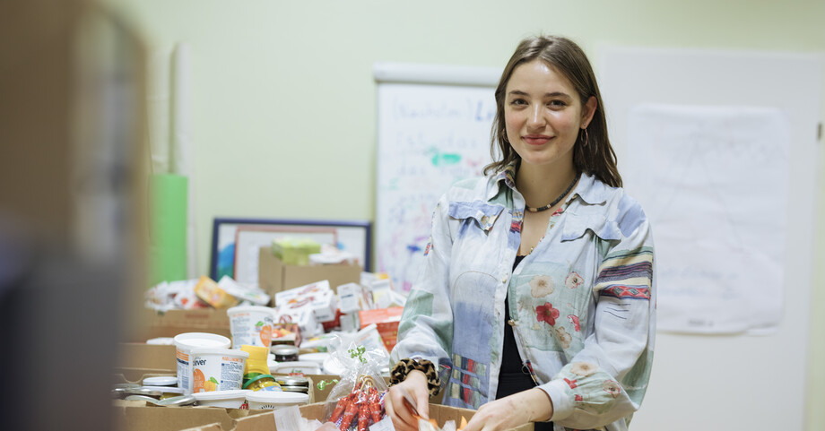 Eine junge Frau sortiert Sachspenden in Kisten 