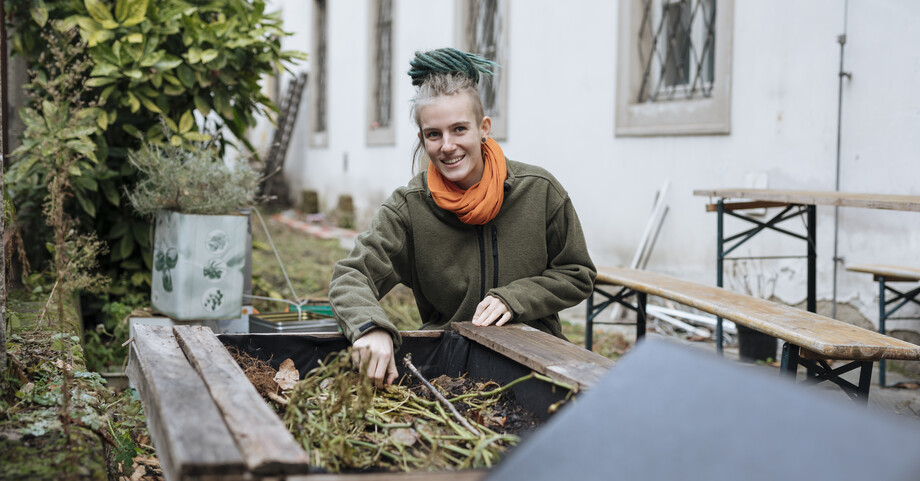 Eine Frau betreut den Biomüll Haufen im Haus Jaro 