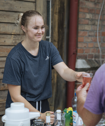 Eine junge Frau verteilt Getränke an Menschen 